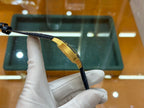 Gold-tone wristwatch with black leather strap, shown from side with case edge
