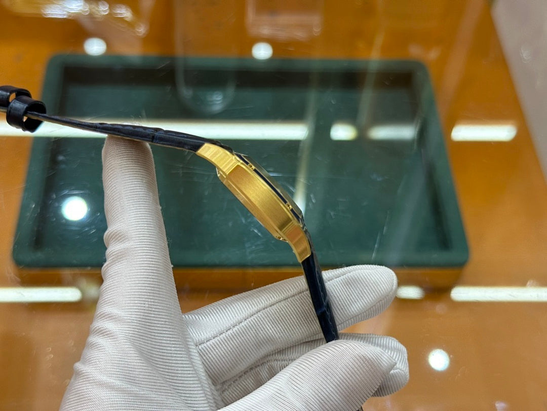 Gold-tone wristwatch with black leather strap, shown from side with case edge