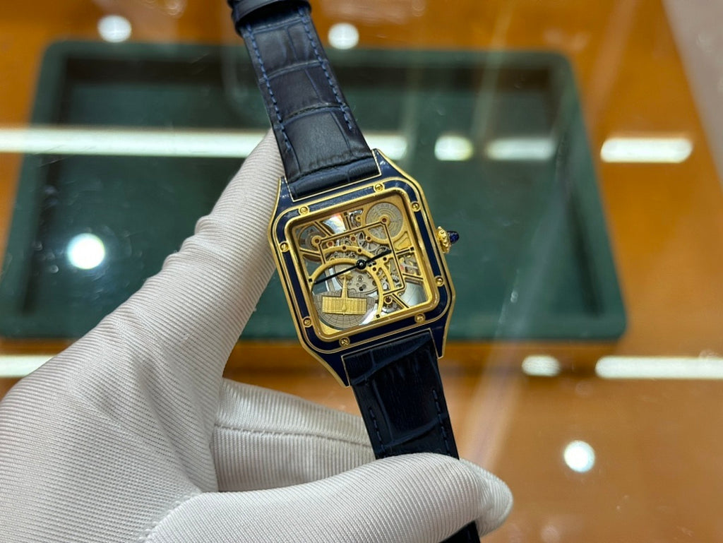 Gold-tone wristwatch with black leather strap and skeleton dial, close side angle