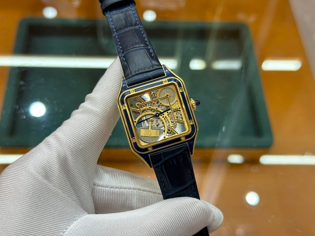Gold-tone wristwatch with black leather strap and skeleton dial, close side angle