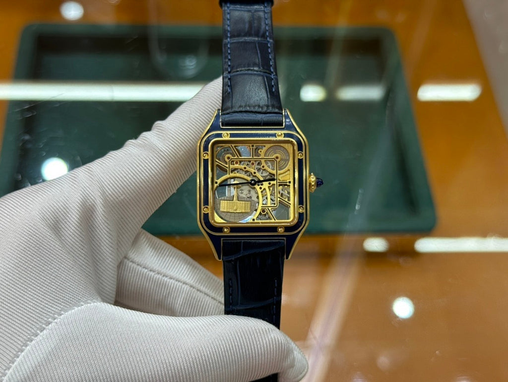 Gold-tone wristwatch with black leather strap and skeleton dial, straight-on view