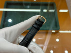 Black leather watch strap with gold-tone buckle clasp and metal ends