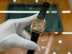 Gold-tone square wristwatch with black leather strap and patterned dial