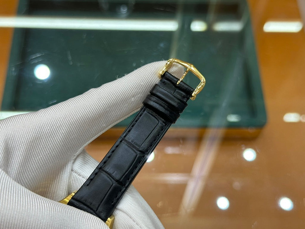 Cartier wristwatch close-up showing black leather strap buckle and gold-tone case