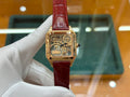 Gold-tone Cartier watch with red leather strap and square skeleton dial