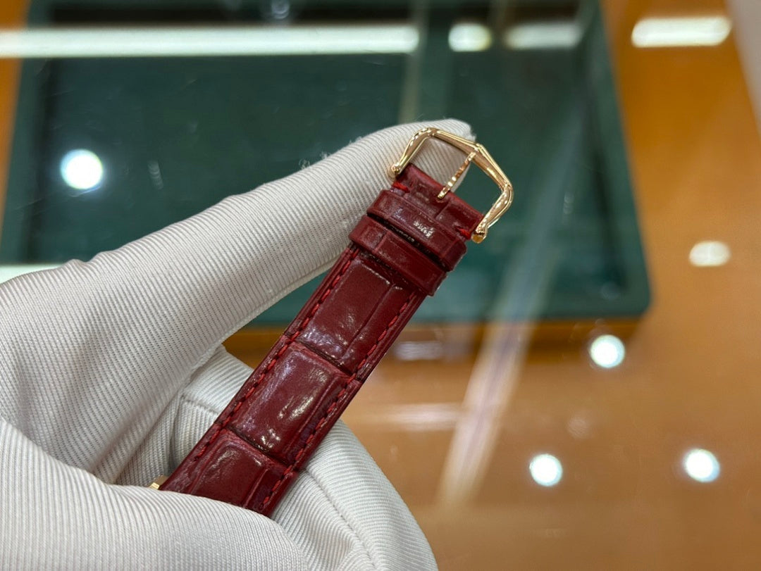 Gold-tone Cartier watch with red leather strap and buckle, side view