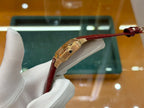 Cartier watch with red leather strap and gold-tone case, crown side view