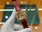 Gold-tone Cartier watch with red leather strap, angled view of square skeleton dial