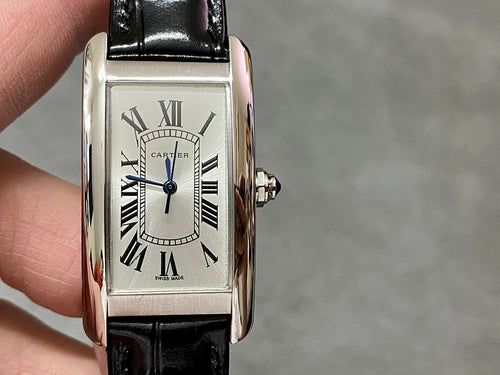 Rectangular wristwatch with silver-tone case, white dial, blue center hand, black leather strap.