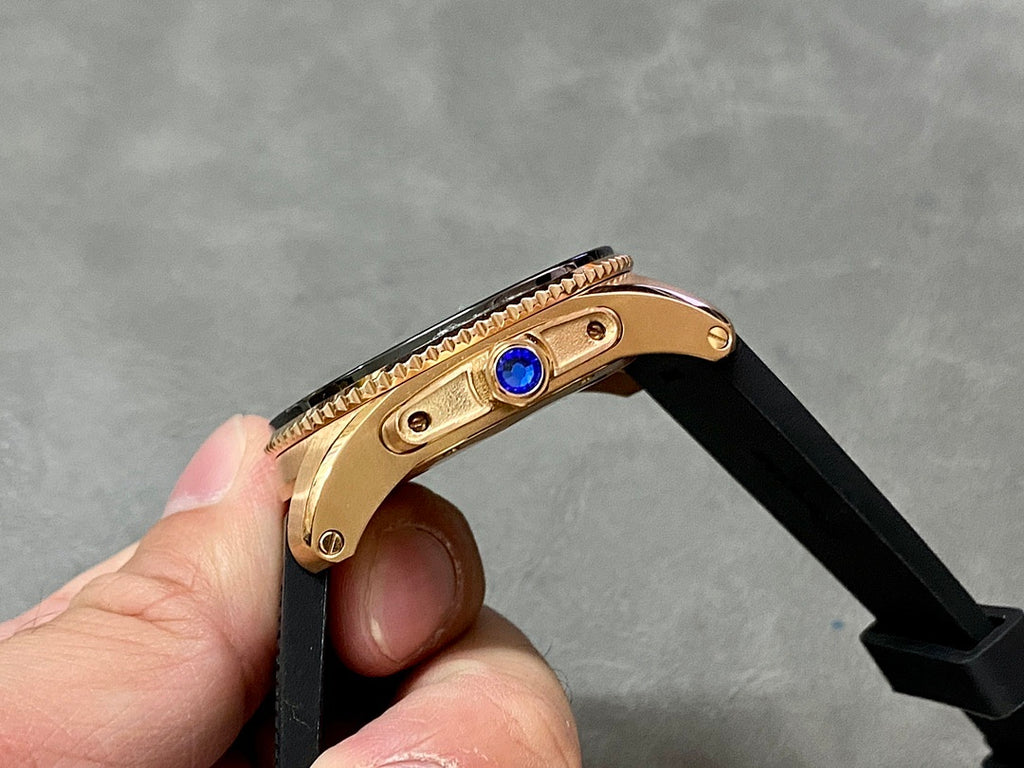 Rose-gold watch case with blue jewel crown on black strap