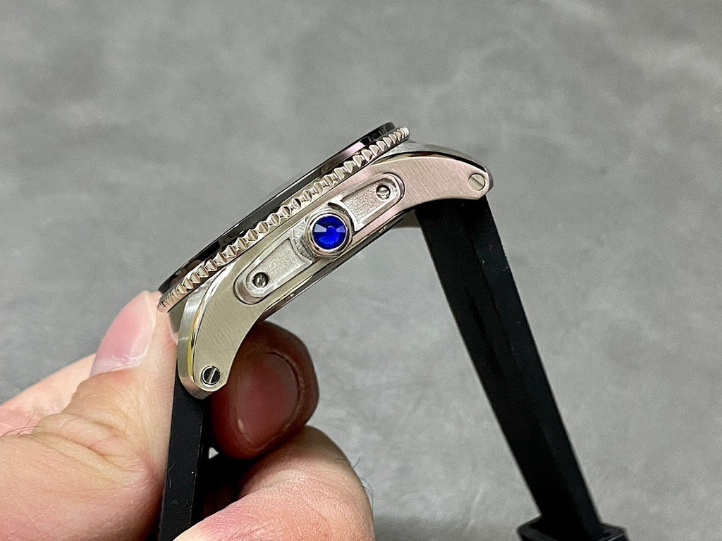 Cartier watch crown detail with blue gemstone on black rubber strap
