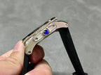 Cartier watch crown detail with blue gemstone on black rubber strap