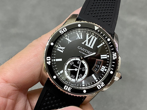 Cartier watch with black dial and Roman numerals, black rubber strap, round stainless case