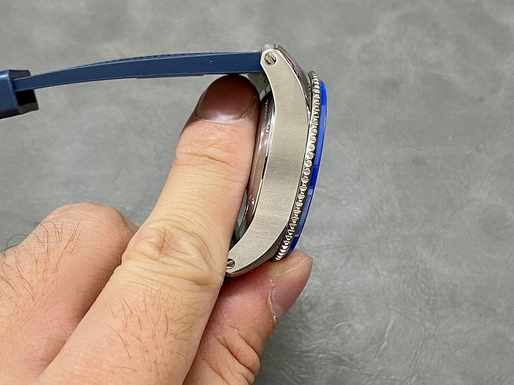 Side profile of blue dive watch with ridged bezel and stainless case edge