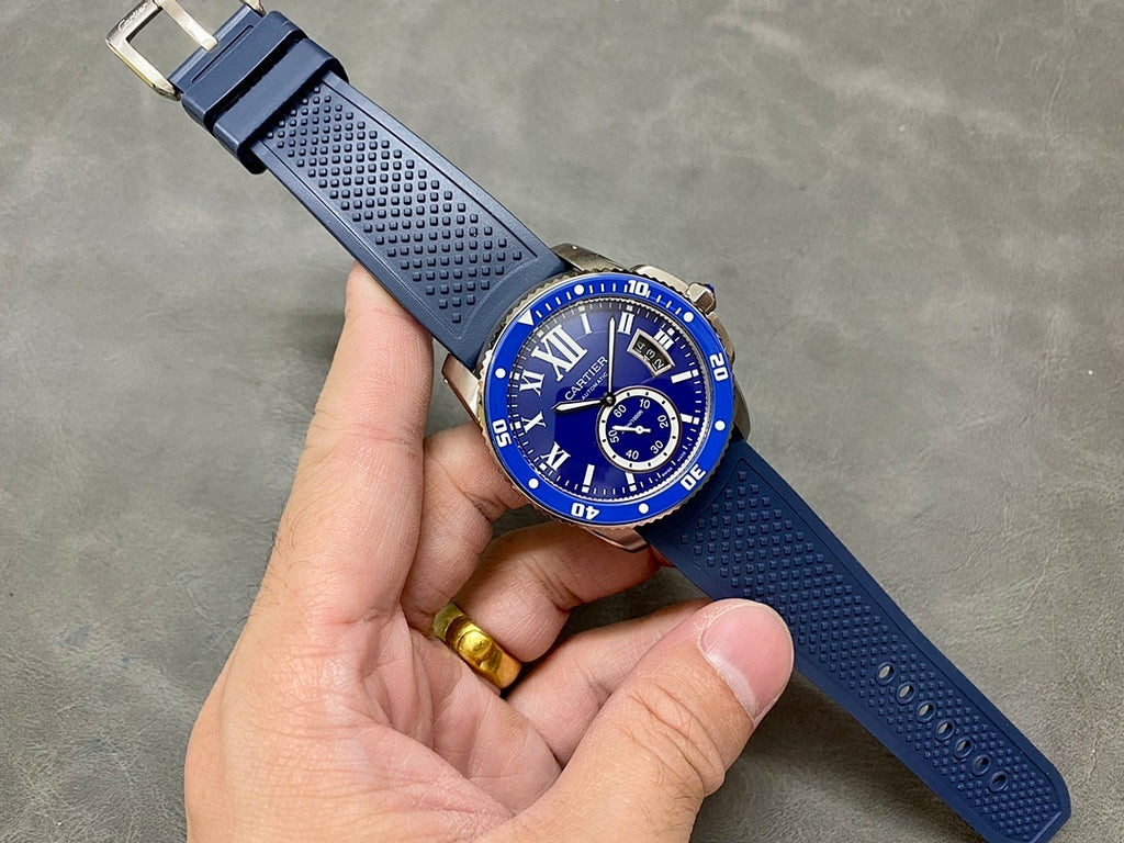 Blue dive-style watch with Roman numerals and silicone strap held in hand