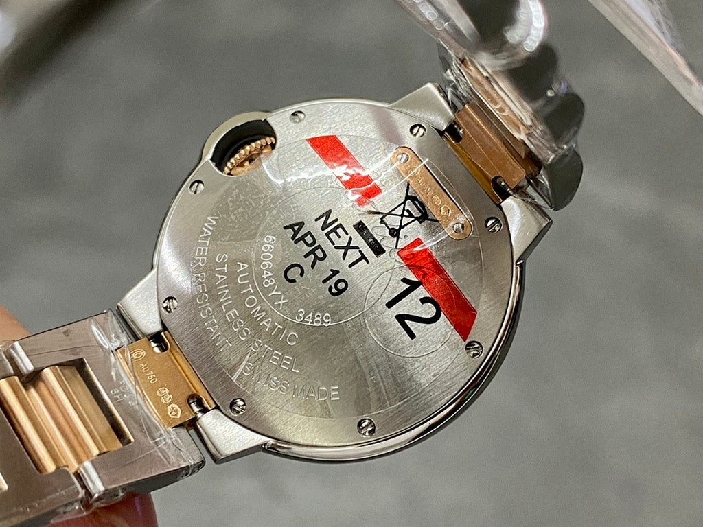 Back of a gold and silver automatic wristwatch with markings and red tag