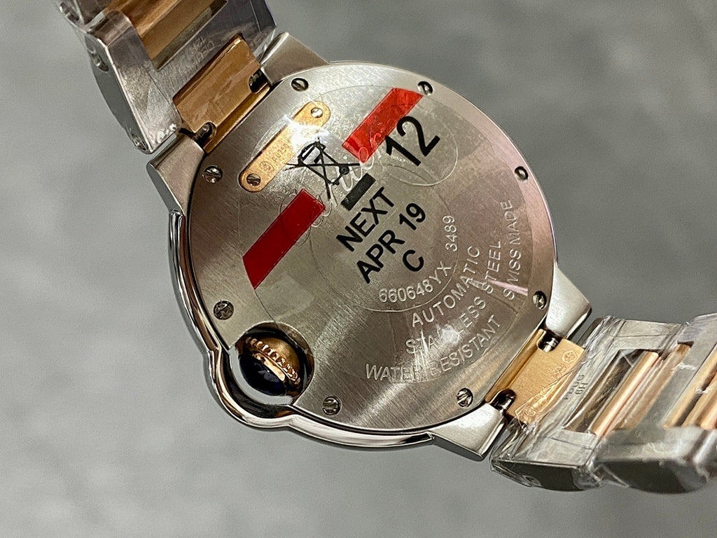 Close-up of watch case back with engraved text, red indicator, and markings