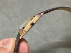 Cartier wristwatch side profile: rose gold case with crown detail, black leather strap