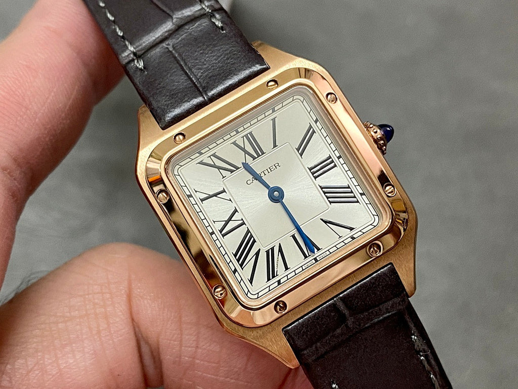Cartier wristwatch close-up: rose gold square case, white dial with Roman numerals, black leather strap