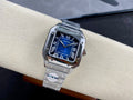 Cartier wristwatch with blue dial, Roman numerals, and steel bracelet on cushion