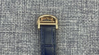 Gold Cartier watch case with blue leather strap, top buckle clasp view.