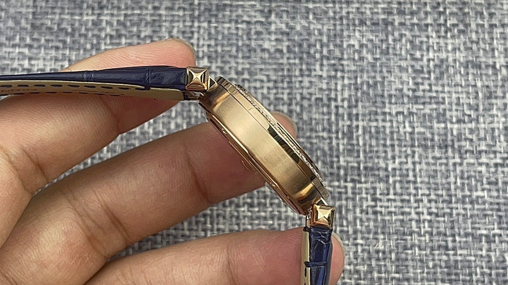 Gold Cartier watch side profile with blue leather strap and gold crown detail.