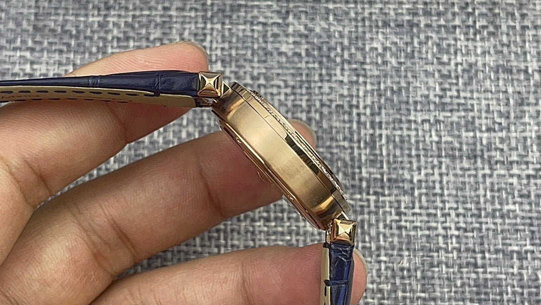 Gold Cartier watch side profile with blue leather strap and gold crown detail.