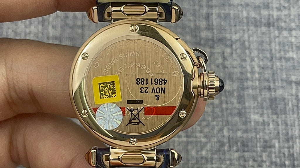 Gold Cartier watch back with engraved case, serial markings, blue leather strap underside.
