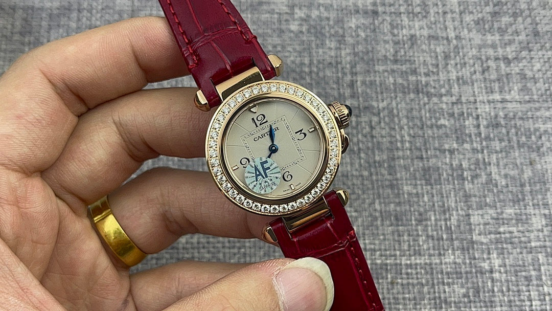 Cartier wristwatch with round gold case, diamond bezel, and red leather strap