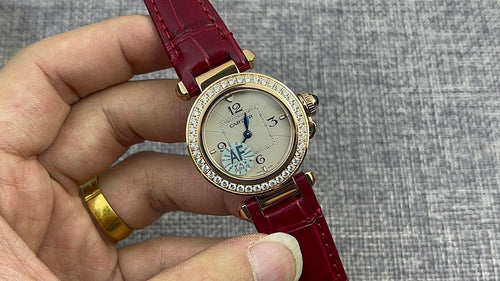 Cartier wristwatch with round gold case, diamond bezel, and red leather strap