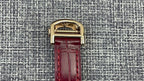 Cartier wristwatch buckle with glossy gold clasp and red leather strap