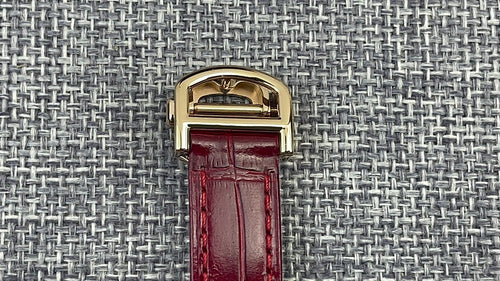 Cartier wristwatch buckle with glossy gold clasp and red leather strap