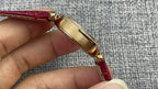 Cartier wristwatch side view with gold case and red leather strap
