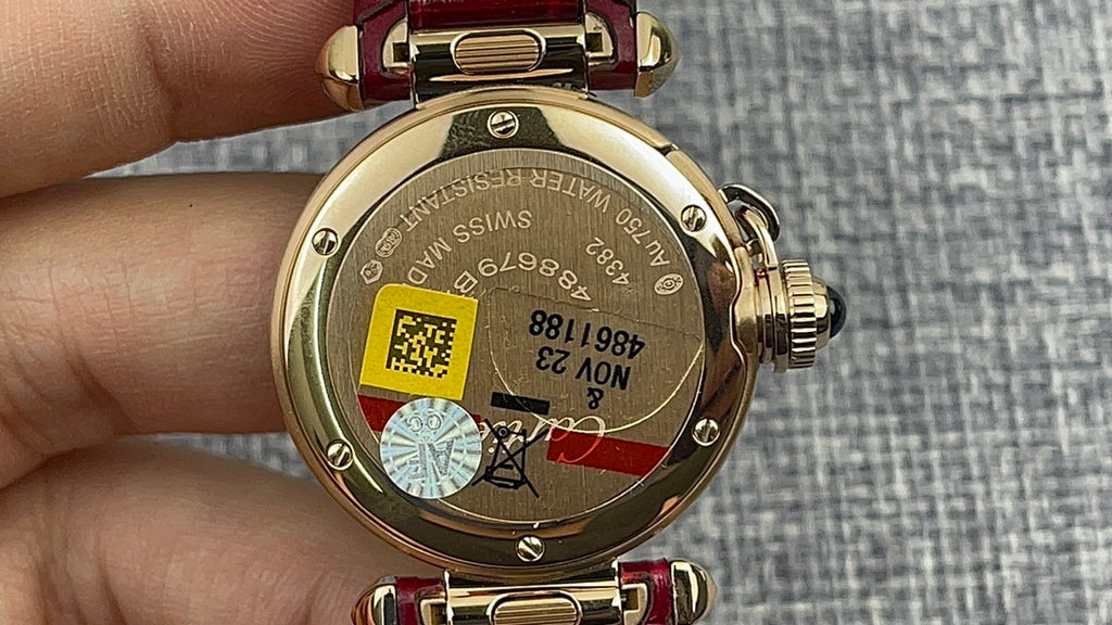 Cartier wristwatch case back with gold finish and red leather strap