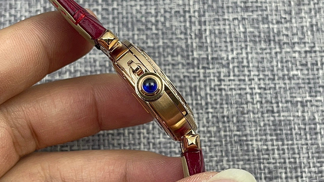 Cartier wristwatch with gold case and blue detail on the side, red leather strap