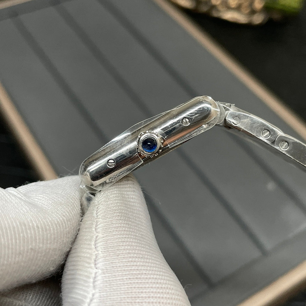 Cartier watch side profile with blue jewel detail on silver-tone case