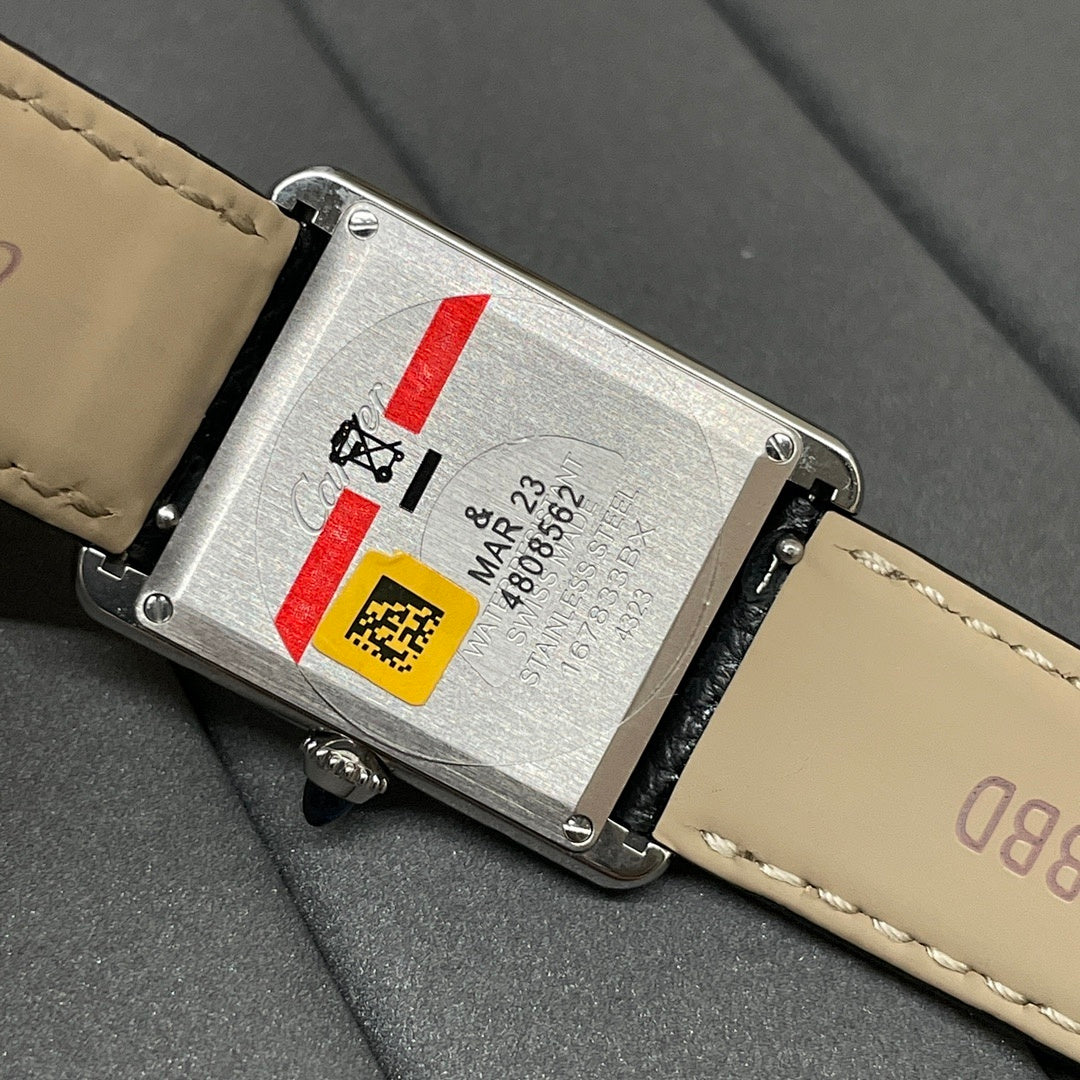 Cartier watch case back close-up with engraved markings; black leather strap with cream stitching.