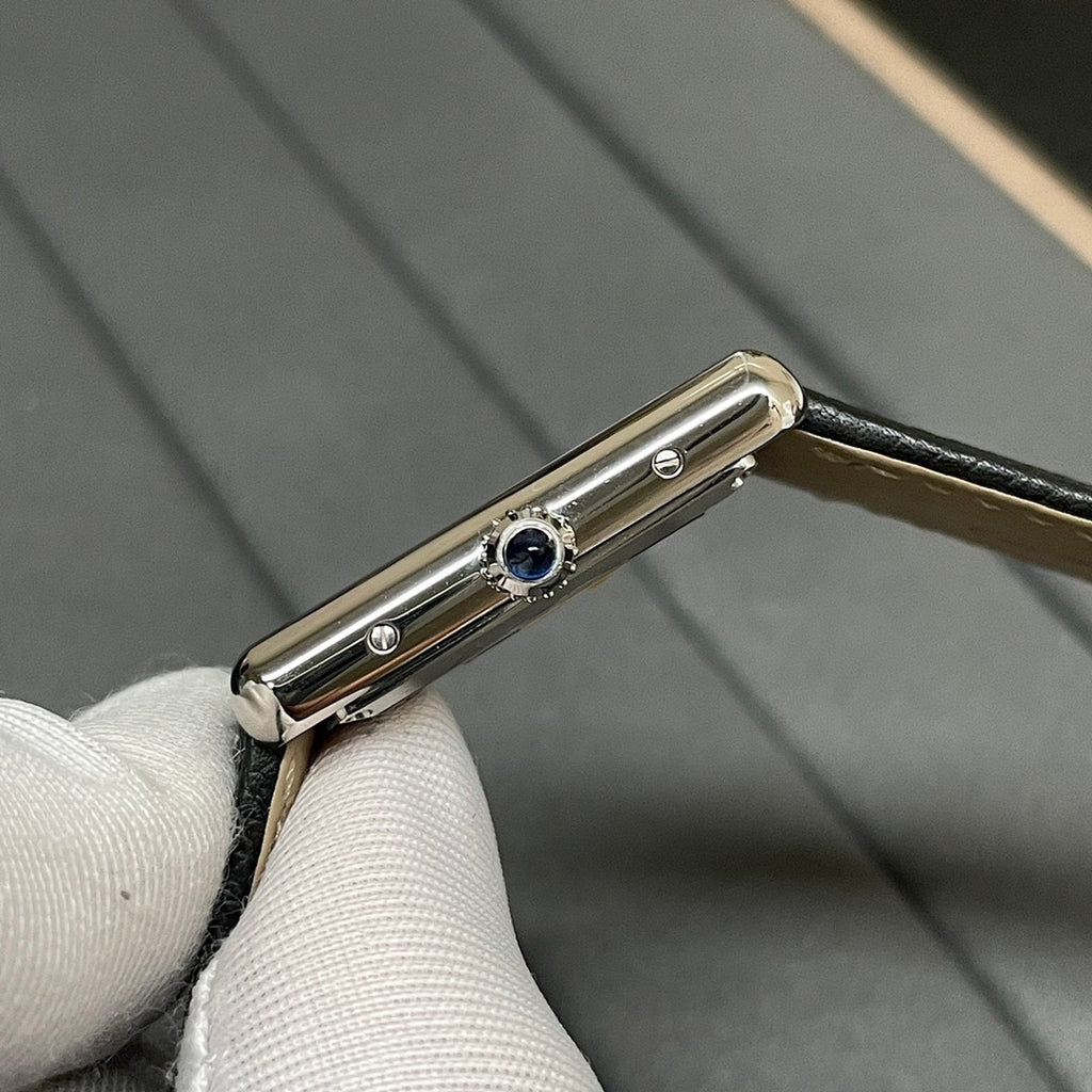 Cartier wristwatch side view with blue detail on the case and black leather strap.