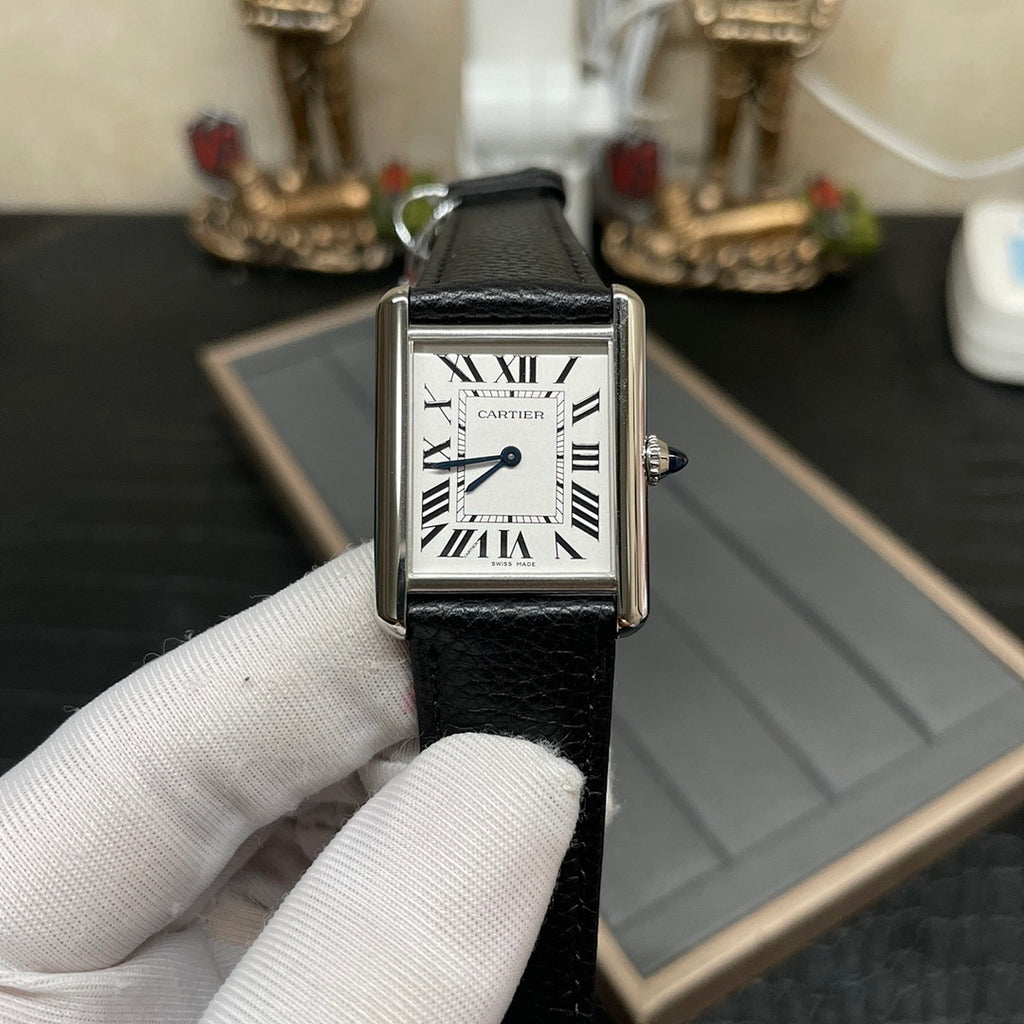 Cartier square wristwatch on black leather strap with silver case, white dial, Roman numerals.
