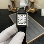 Cartier square wristwatch on black leather strap with silver case, white dial, Roman numerals.