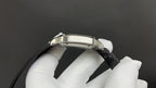 Cartier wristwatch side view with silver case and black leather strap.