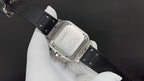 Cartier watch angled on black strap, showing engraved case back and clasp