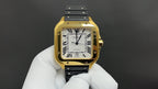 Gold Cartier watch with black leather strap and white dial, Roman numerals, visible hands