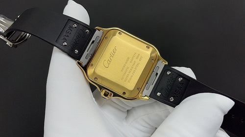 Gold watch case with black strap, clasp and engraved case back visible