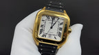 Gold Cartier watch front view with black strap, Roman numeral dial and minute marks