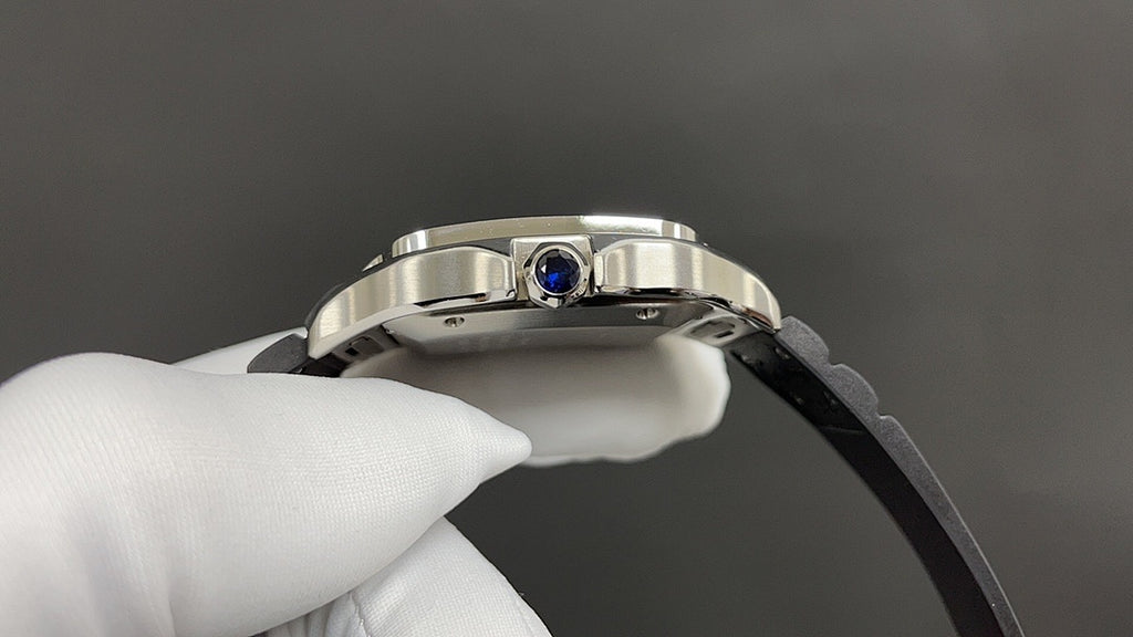 Cartier wristwatch crown with blue gemstone on silver case, black rubber strap
