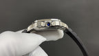 Cartier wristwatch crown with blue gemstone on silver case, black rubber strap