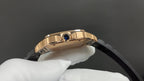 Cartier watch with blue crown detail on gold-toned bezel and black strap