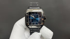 Cartier Santos watch with blue dial and black strap, held in white gloves.
