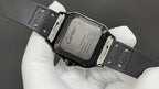Cartier watch case with clasp and engraved back, black strap on white gloves.